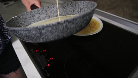 Close-up-view-of-female-hands-pouring-pancake-Mixed-in-a-frying-pan-and-spreading-it-around.-Homemade-food.-Slow-Motion-shot
