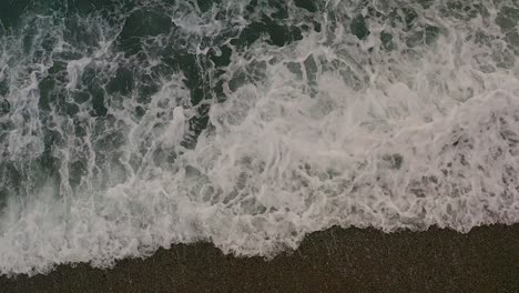 turquoise ocean water waves raging over coastal shoreline beach top view from aerial drone in philippines