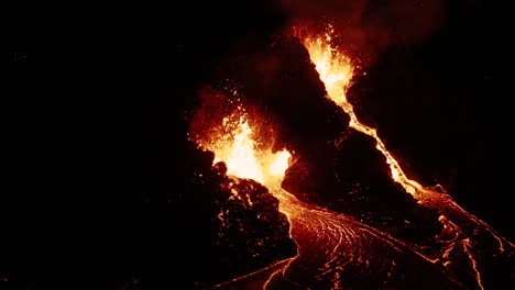 magma fundido brillante que sale de dos aberturas en la corteza terrestre por la noche
