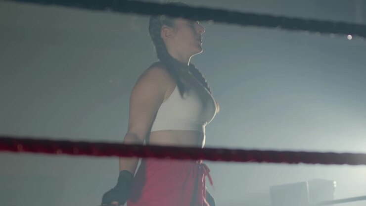 Giovane sportiva caucasica con codini intrecciati che salta la corda sul ring da boxe