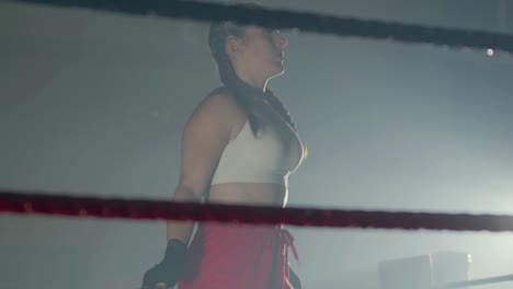 young caucasian sportswoman with braided pigtails jumping rope in boxing ring