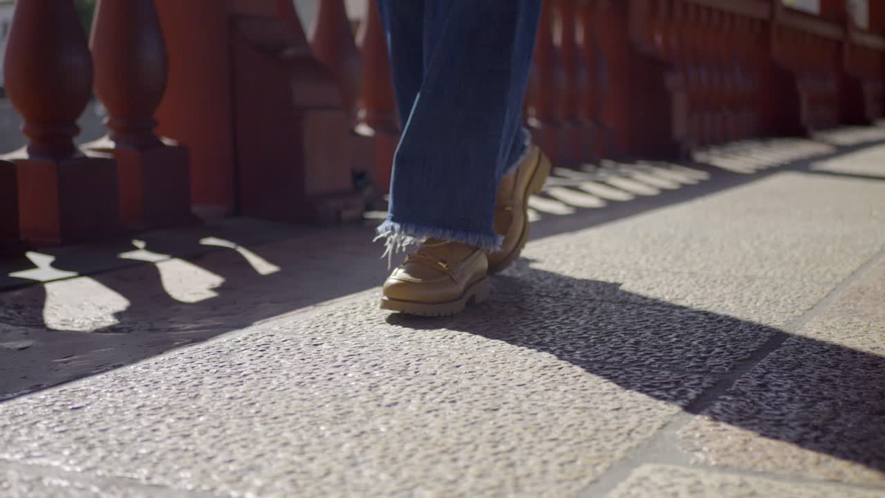 Tracking Ground Shot Of Lady Wearing Stylish Jeans With Casual Shoes Walking On Bridge