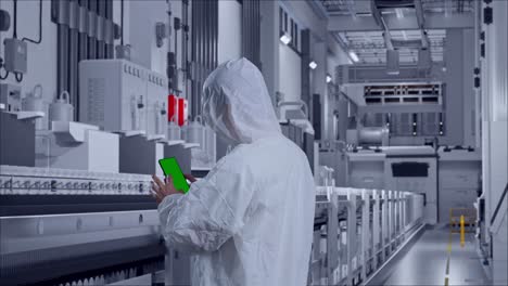 back view of asian male scientist use mock up green screen smartphone while standing at pharmaceutical factory, vaccine production facility
