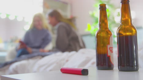 two teenage girls in bedroom with bottles of beer and vape pen in foreground