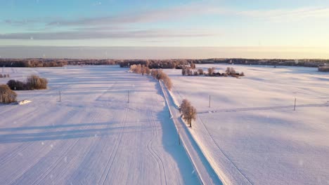 romantic sunset over pure white snowy landscape during snowfall, aerial view