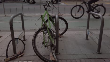 vandalized bike with bent wheel locked by bicycle lane as cyclists pass, slowmo