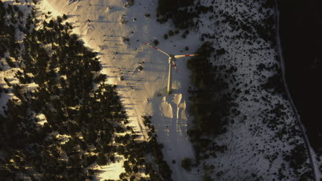 Birdseye-aerial-shot-of-snow-covered-plateau-showing-a-wind-turbine