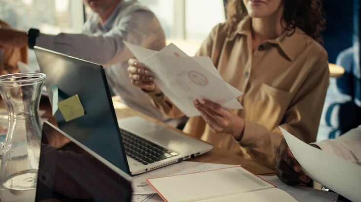 Shooting up close: Office workers pass each other sheets of paper with their projects. A girl in a light brown shirt shows work