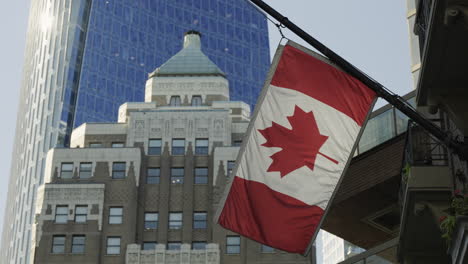 canadian flag hanging at house and waving in the wind in downtown vancouver, handheld static slow-motion