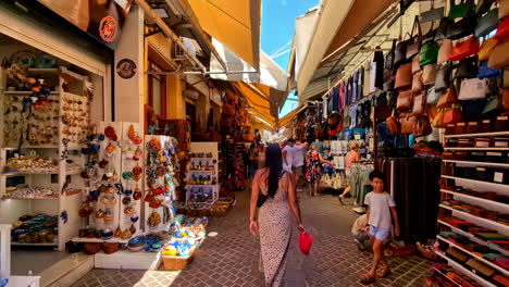 people and tourists walking and looking at products at a street market with many stalls with crafts and souvenirs from chania in crete greece