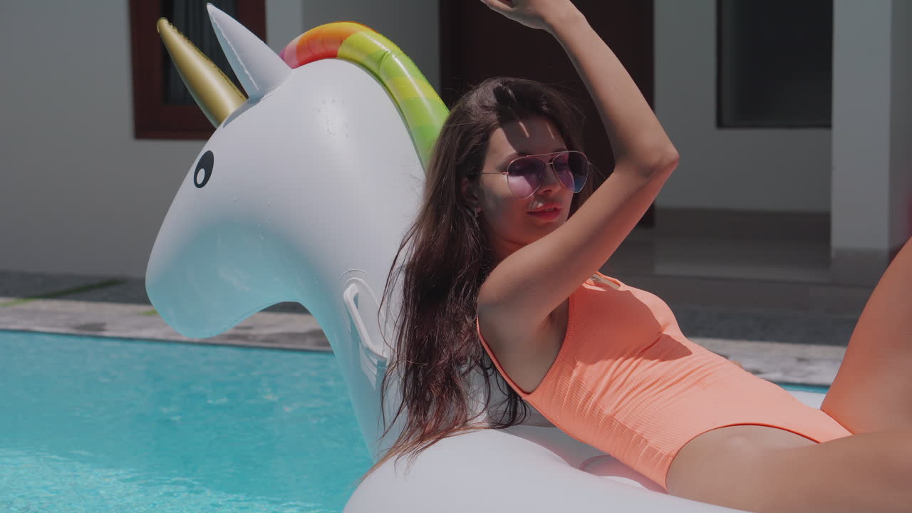 Woman Relaxing in Pool with Inflatable Unicorn
