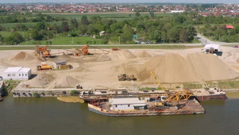 barge and tractors at sand quarry by the river in serbia