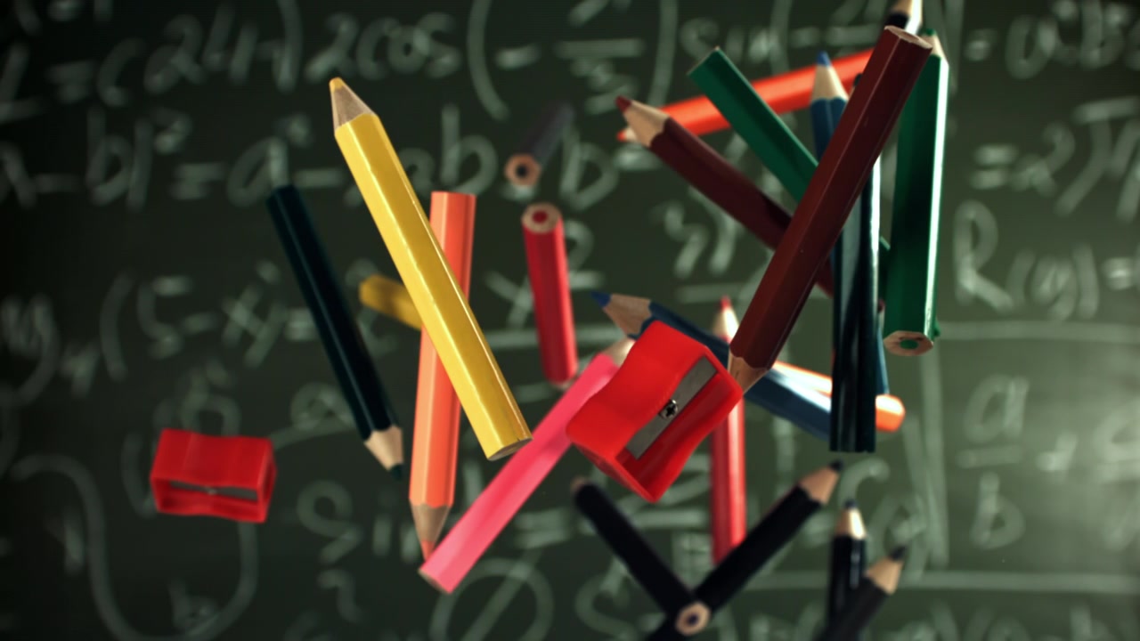 Kolorowe ołówki i temperówki unoszące się na tle tablicy matematycznej