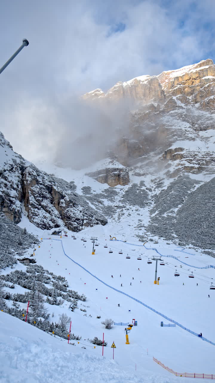 Distant view of people skiing at a ski resort near a ski lift in the Dolomites, Italy. Vertical