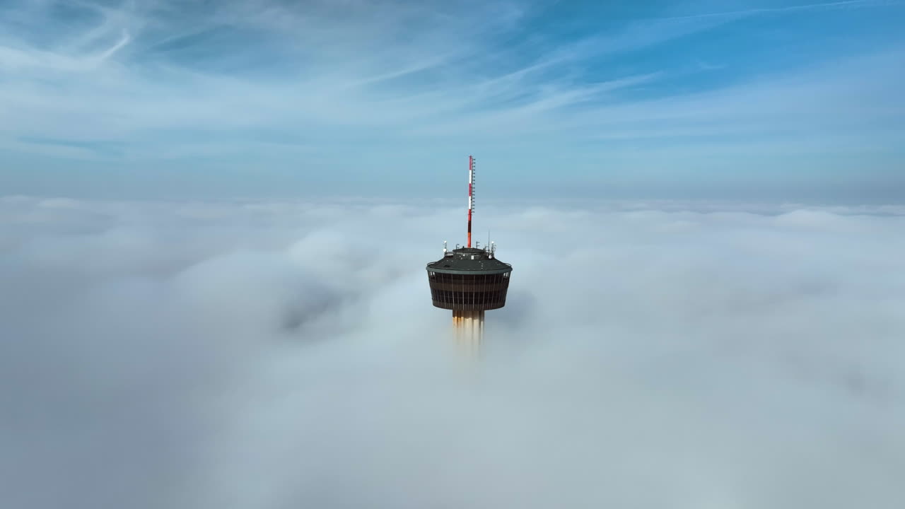 Panoramic drone shot orbiting the Tower of the Americas, misty day in San Antonio