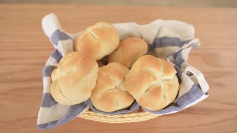 Top-Down-View-of-Freshly-Baked-Kaiser-Bread-on-Striped-Towel-in-Wooden-Basket