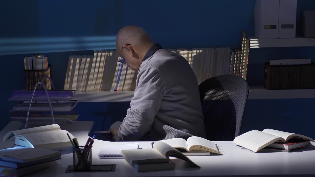 Clever researcher old man reading at his desk, following scientific research.