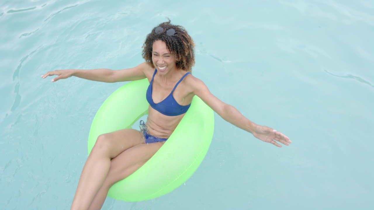Biracial woman enjoys a sunny day in the pool