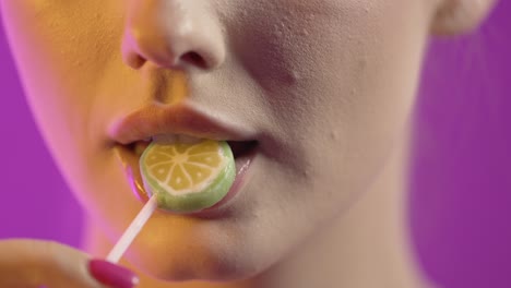 woman licking popsicle with seduction, mouth close-up shot on purple background