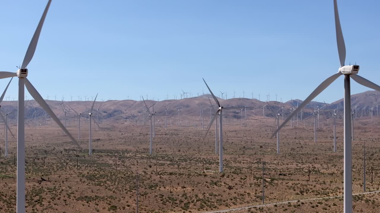 Turbines on a wind farm generate sustainable electricity in California's Mojave Desert - sliding aerial