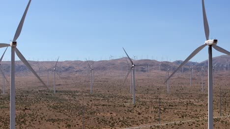 turbines on a wind farm generate sustainable electricity in california's mojave desert - sliding aerial