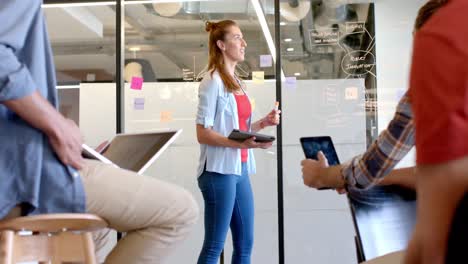 happy caucasian casual businesswoman presenting to diverse colleagues at glass wall, slow motion