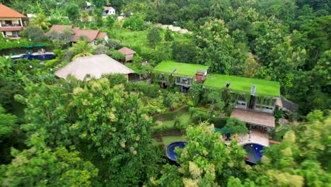 4k drone video of an eco hotel in north bali indonesia, with a big blue swimming pool surrounded by green natural landscapes