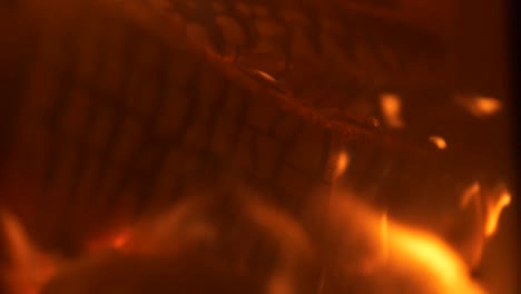 Log fire close up, detailed shot of glowing log and flames flickering
