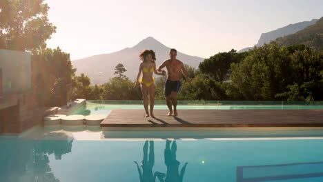 pareja feliz saltando a la piscina al aire libre