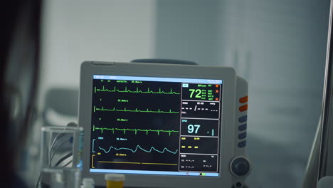 Woman-holding-patient-hand-in-ward-closeup.-Hospital-heartbeat-computer-screen.
