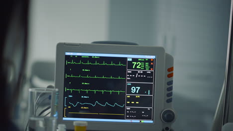 woman holding patient hand in ward closeup. hospital heartbeat computer screen.