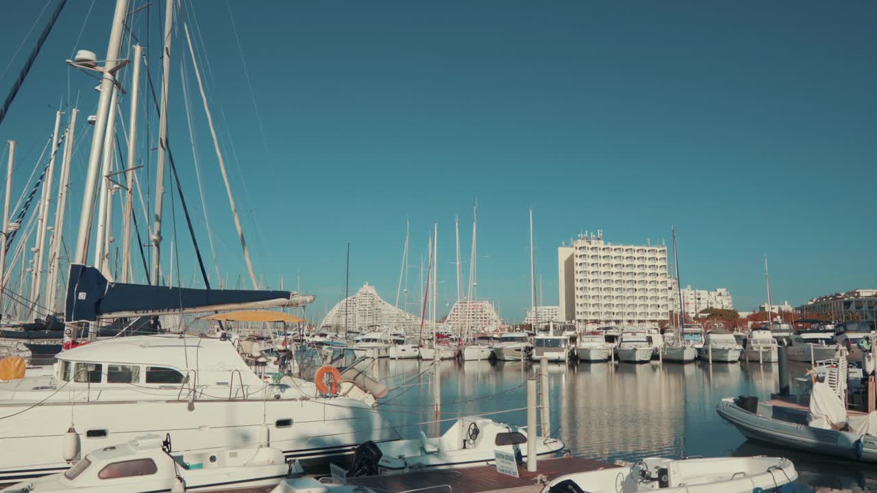 Eine geparkte Grande Mottes Yacht schaukelt an einem schönen Tag auf dem Wasser, mit Gebäuden.