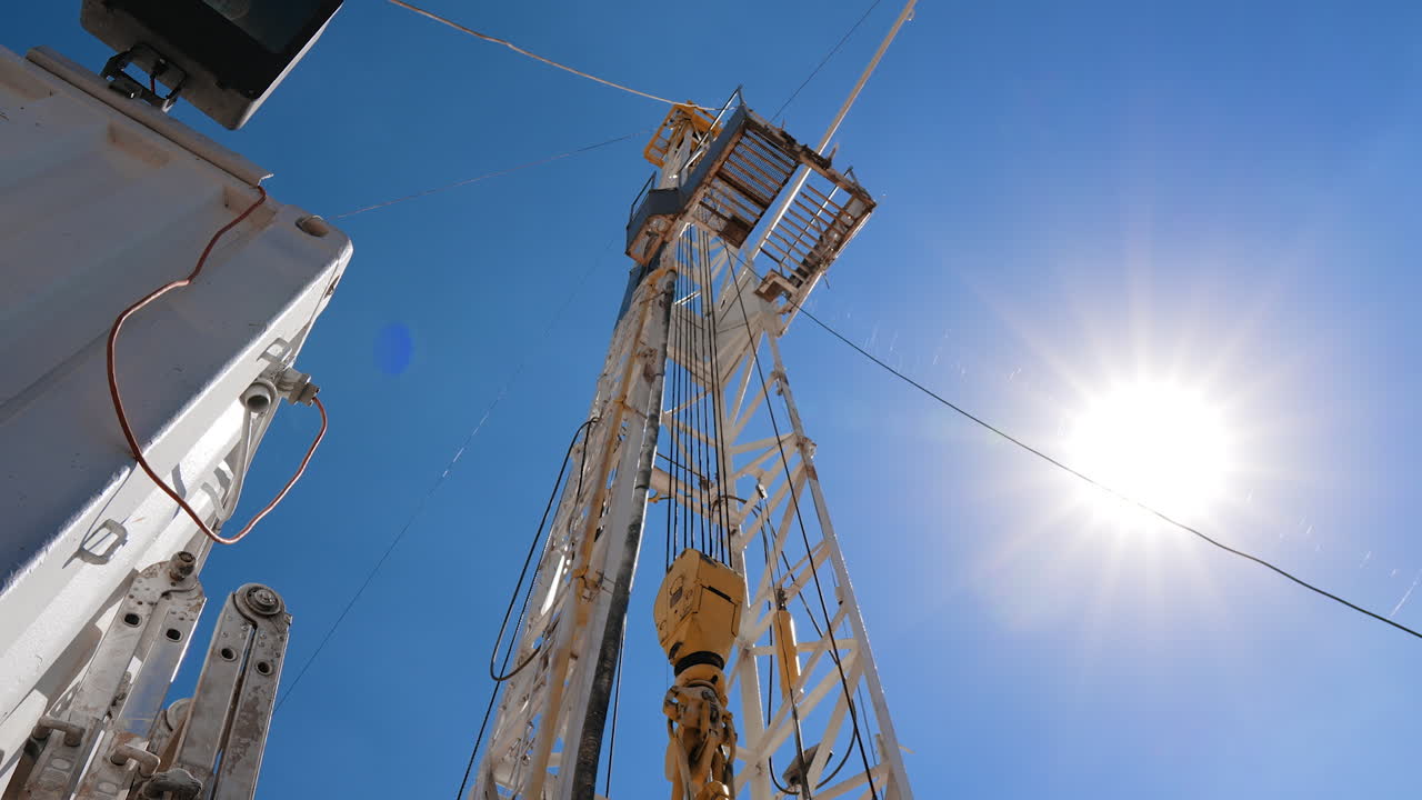 Tower with drilling bour in the oil production site. Footage at the wagon on the location. Low angle view.