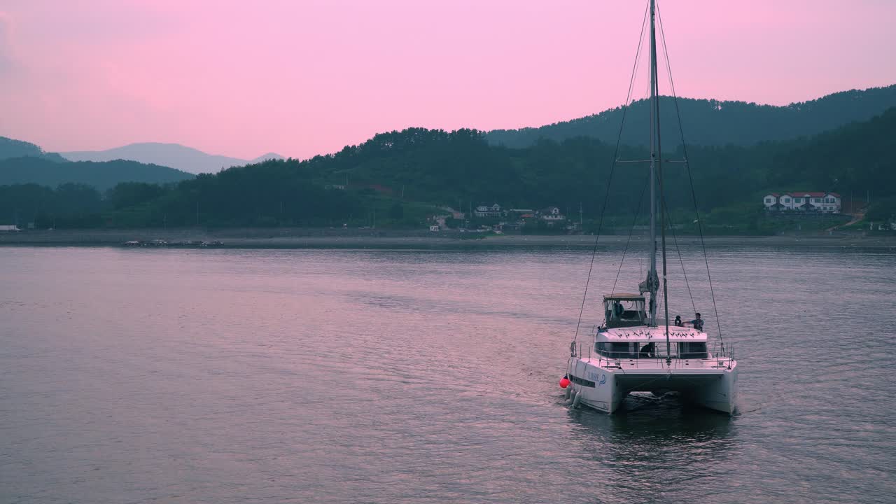 Turisti su un catamarano che arrivano al resort sull'isola di Geoje durante un tramonto rosa in Corea del Sud
