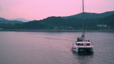 tourists on catamaran boat arriving at the resort in geoje island during pink sunset in south korea