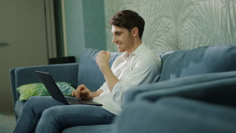 hombre alegre usando una computadora en el hotel. hombre guapo leyendo un mensaje en su portátil.