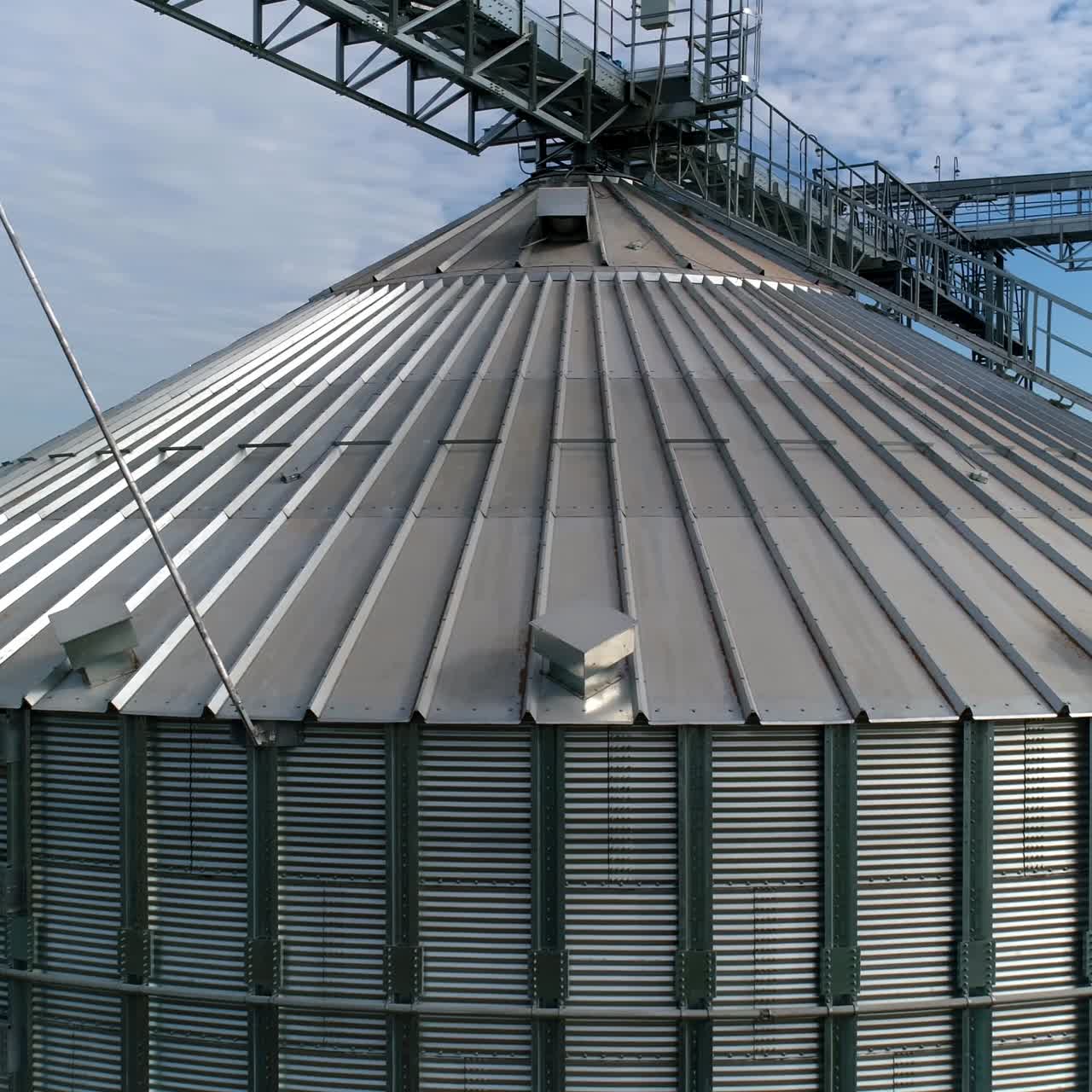 Modern plant for agribusiness. Large grain terminals on nature background. Silver grain elevators. Aerial view. Camera moves around.