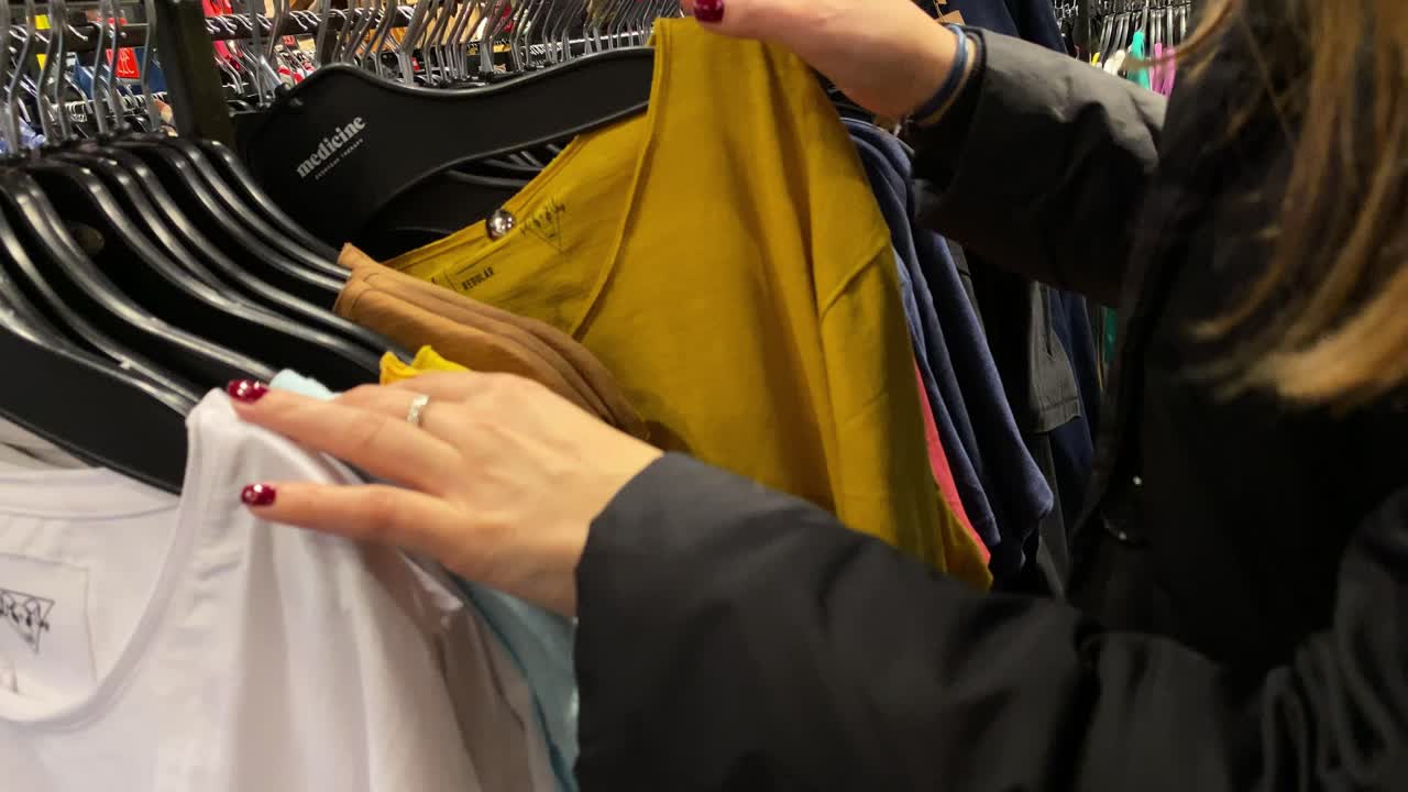 The girl is looking at clothes on hangers in the MEDICINE store