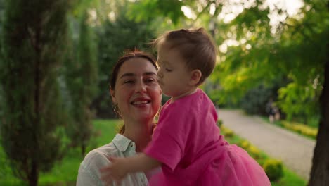una madre y su hija están sonriendo y divirtiéndose en un parque.