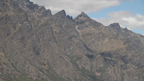 Tiny-plane-turning-around-in-front-of-giant,-rugged-cliff