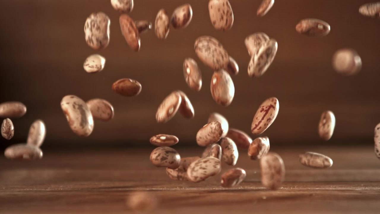 Fagioli pinto che cadono al rallentatore su una superficie di legno