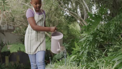 Fröhliches-Afroamerikanisches-Mädchen,-Das-Pflanzen-Im-Garten-Gießt,-Zeitlupe