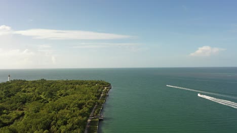 Ein-Flug-über-Die-Küste-Eines-Strandes-Mit-Motorbooten-Am-Horizont