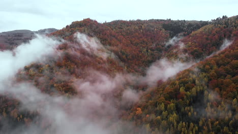 Drone-De-Vista-Aérea-Volando-A-Través-De-Las-Nubes-Revelando-Colinas-De-Bosque-De-Color-Otoñal,-Estableciendo-Tiro