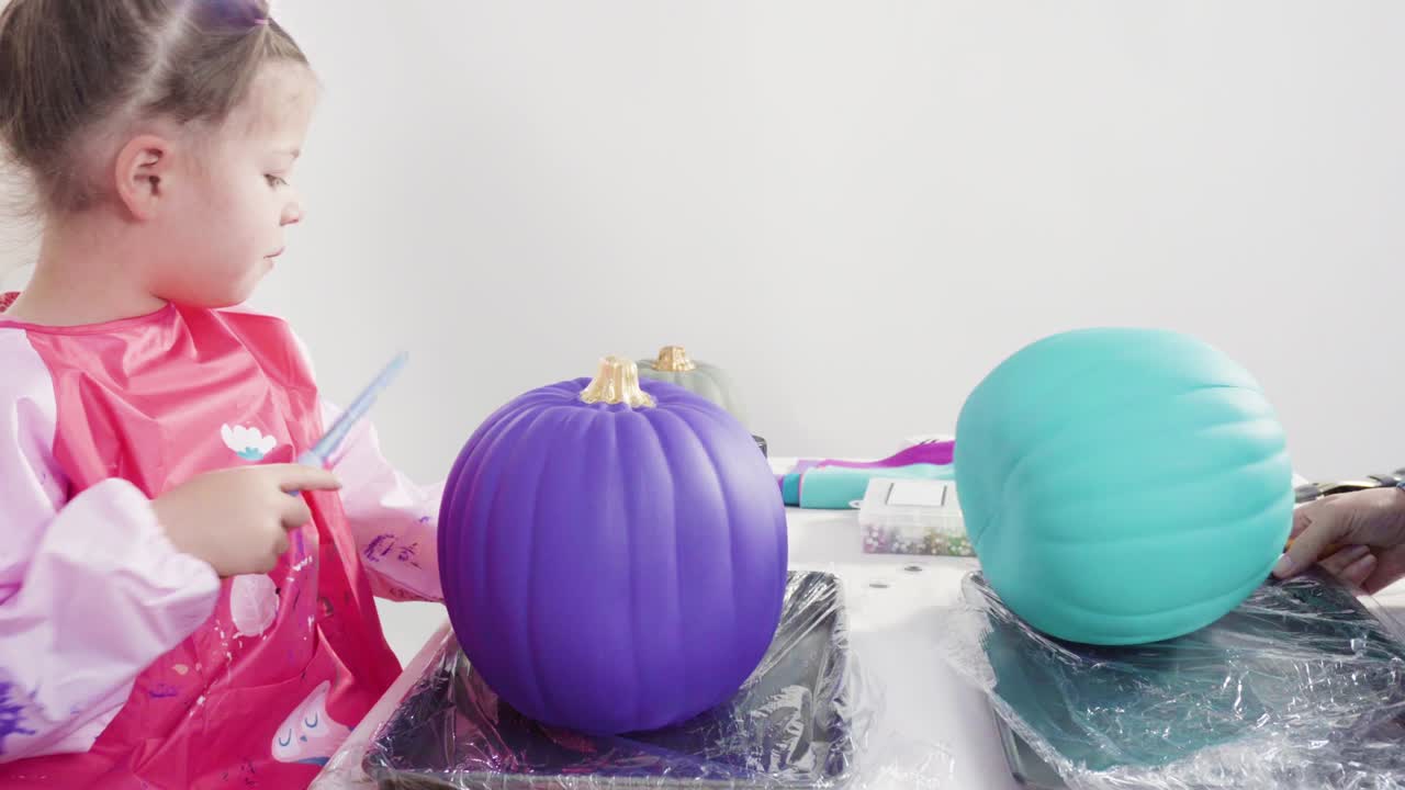 엄마와 딸이 미술 호박을 장식하고 있습니다.