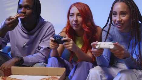 Group-Of-Gen-Z-Friends-Sitting-On-Sofa-At-Home-Gaming-And-Eating-Takeaway-Pizza-2