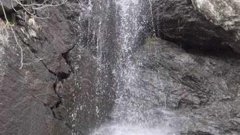 water falling down from a medium waterfall with dark brown rocks