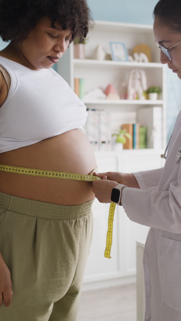Pregnant woman getting her belly measured by a doctor