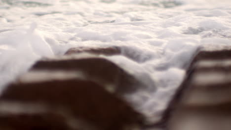 Close-ip-of-ocean-sea-waves-crashing-on-shaped-rock-on-beach