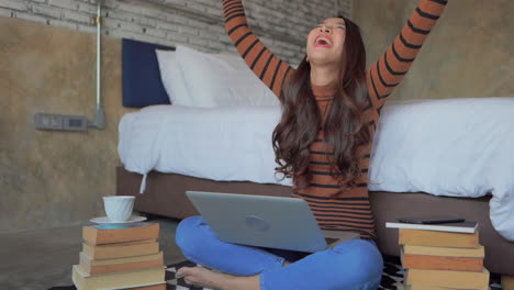 asian girl student won the prize, lottery, got the best score on exams, winning expression, sitting on the floor with a notebook